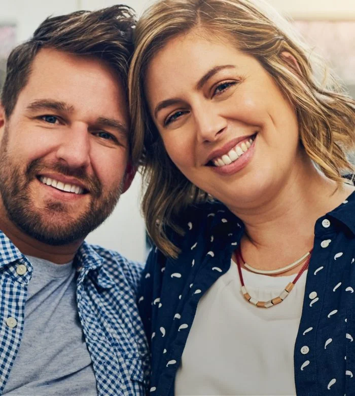 Smiling man and woman close together wearing casual clothes indoors.