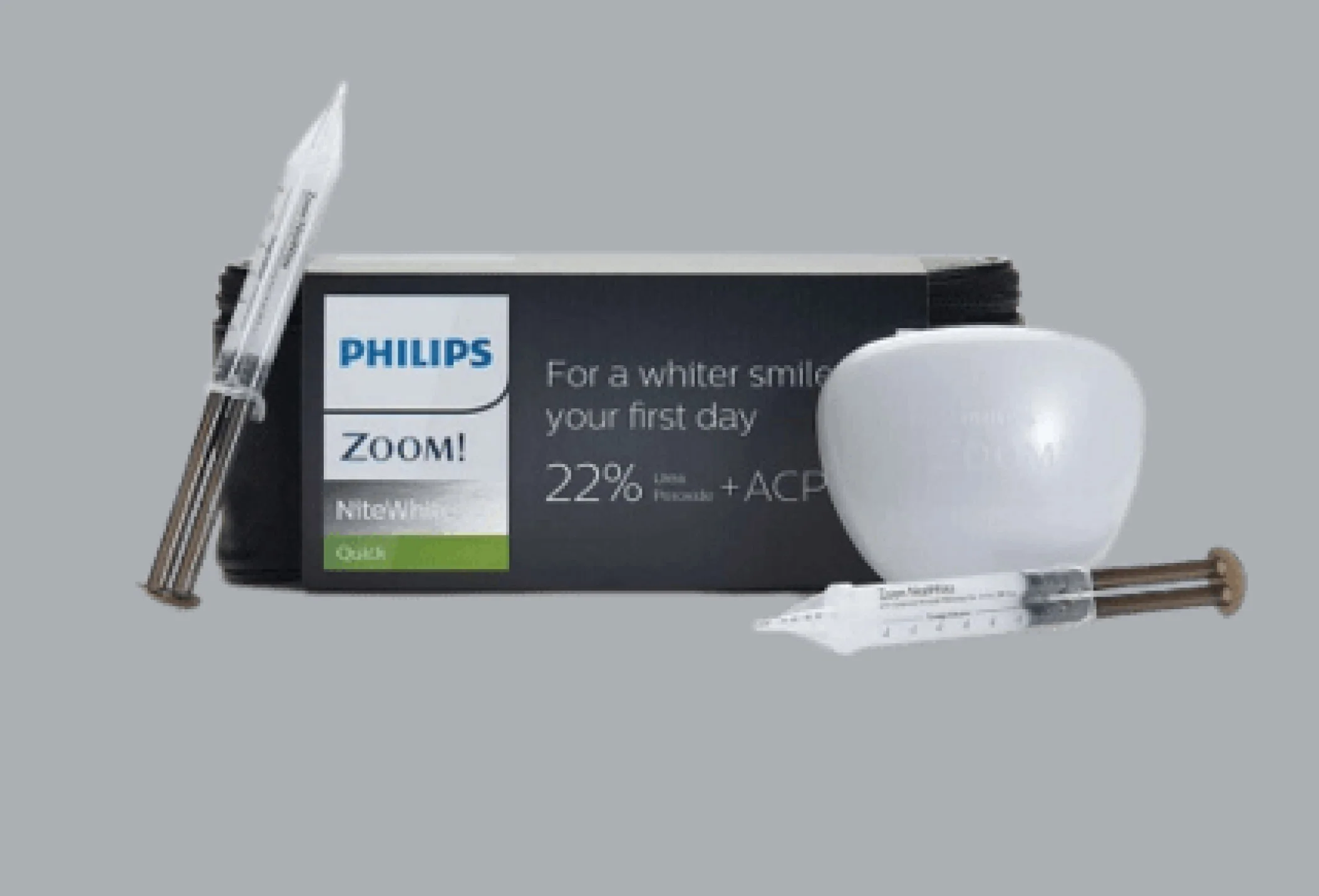 Philips Zoom teeth whitening kit with syringes and a white teeth model against gray background.