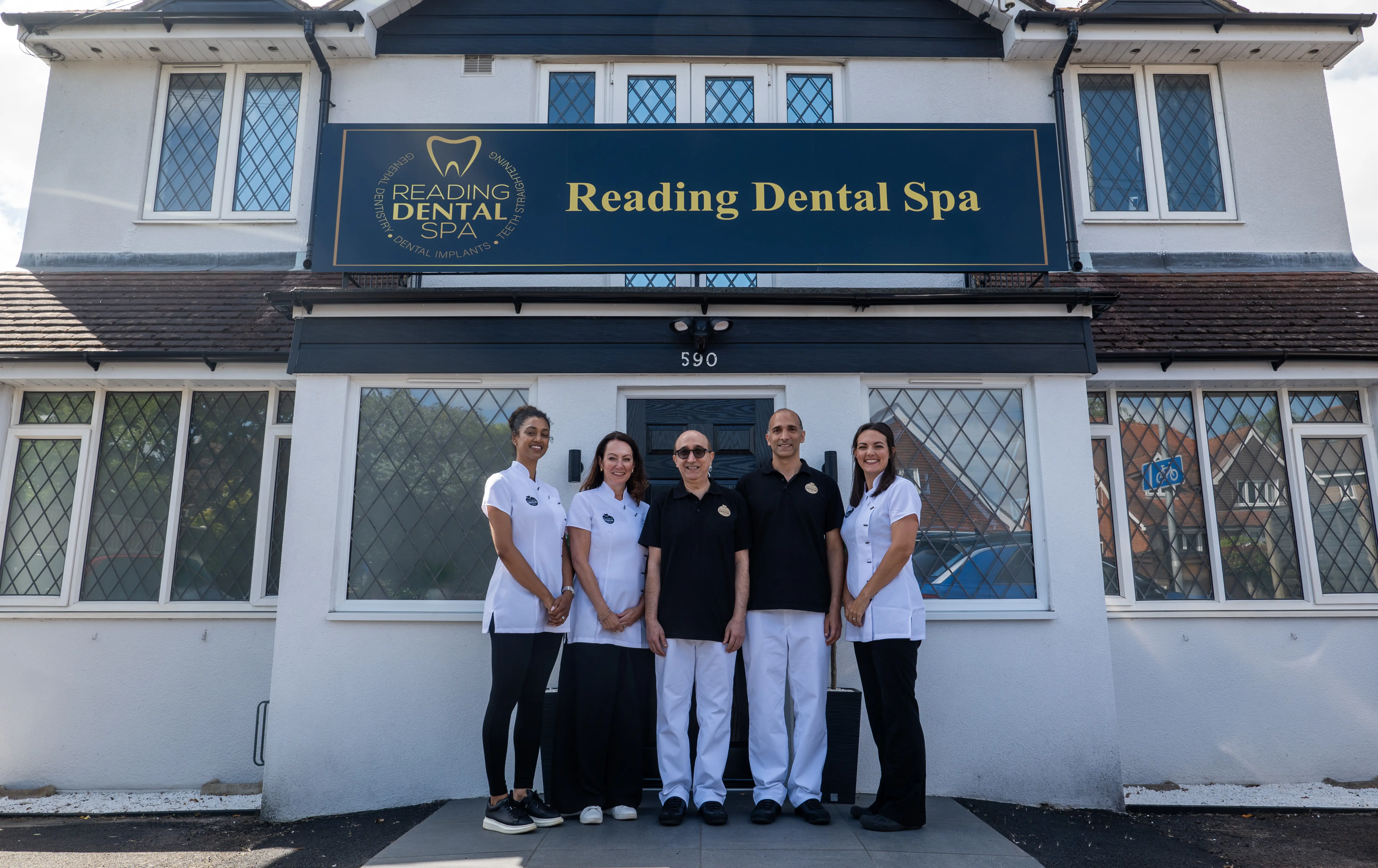 Five dental staff posing outside Reading Dental Spa under the clinic's sign at entrance.