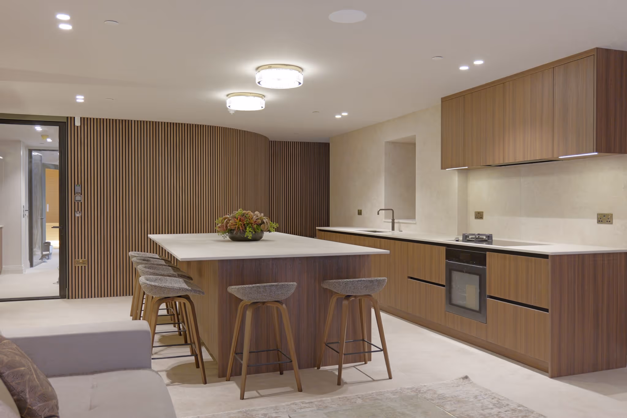 Modern kitchen with wood cabinets, large island with bar stools, and neutral-toned walls and floor.
