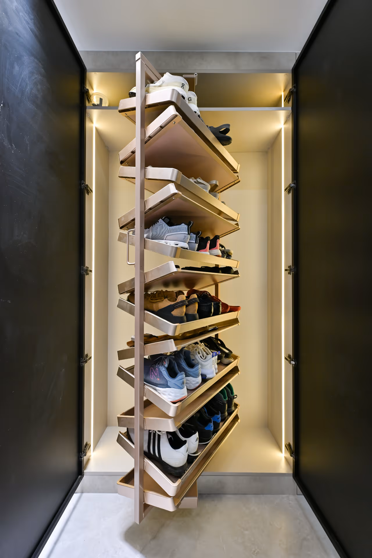 Rotating shoe rack inside a cabinet holding multiple pairs of shoes, lit with vertical LED strips.