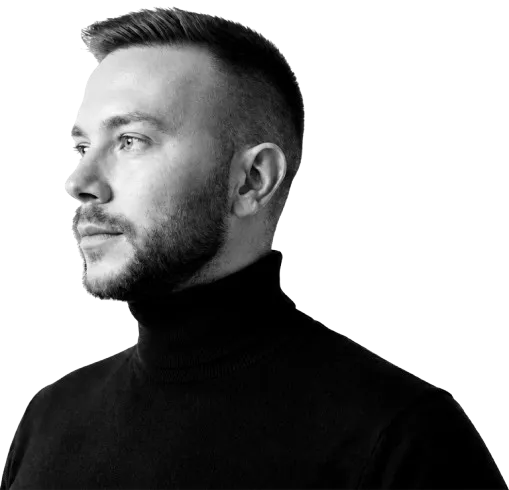 Side profile of a man with short hair and beard wearing a black turtleneck, looking left.