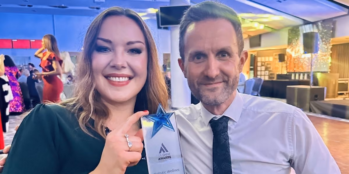 Two smiling Fedcap Clubhouse colleagues at an awards event, holding a star-shaped trophy.