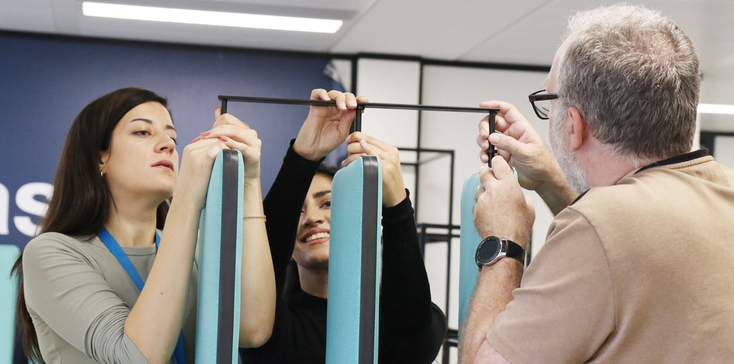 Three colleagues work together to assemble a piece of exercise equipment.