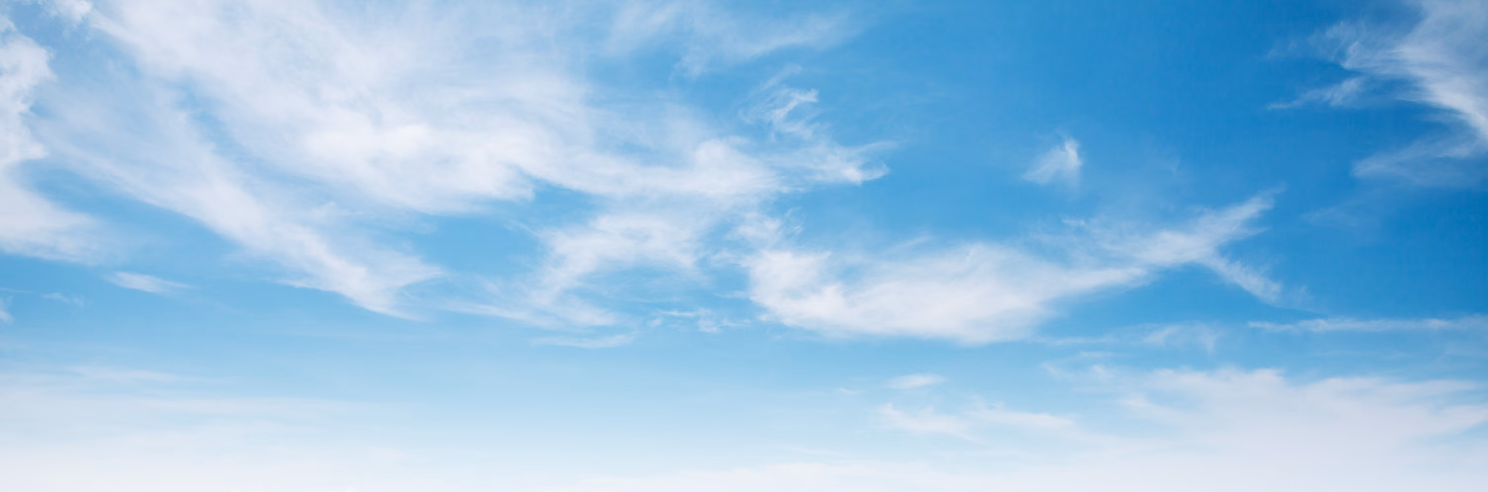 A blue sky with wispy white clouds.