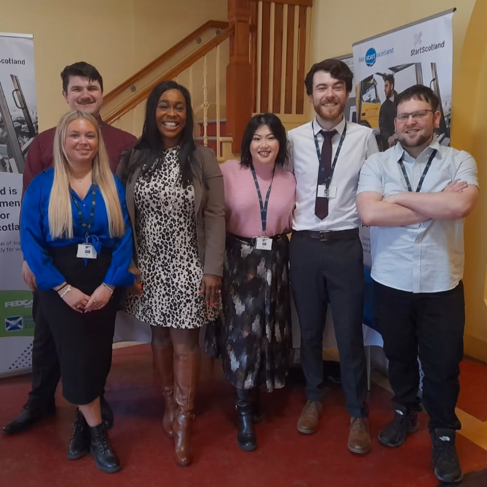 Six Fedcap colleagues pose together at an indoor event.