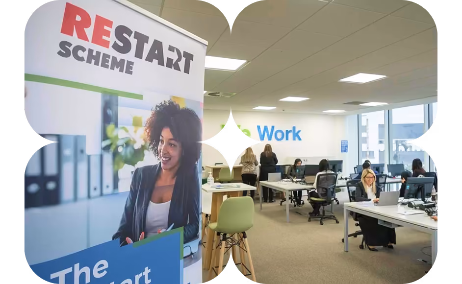 A “Restart Scheme” banner stands in an office with a “We Work” wall graphic and people working at desks behind it.