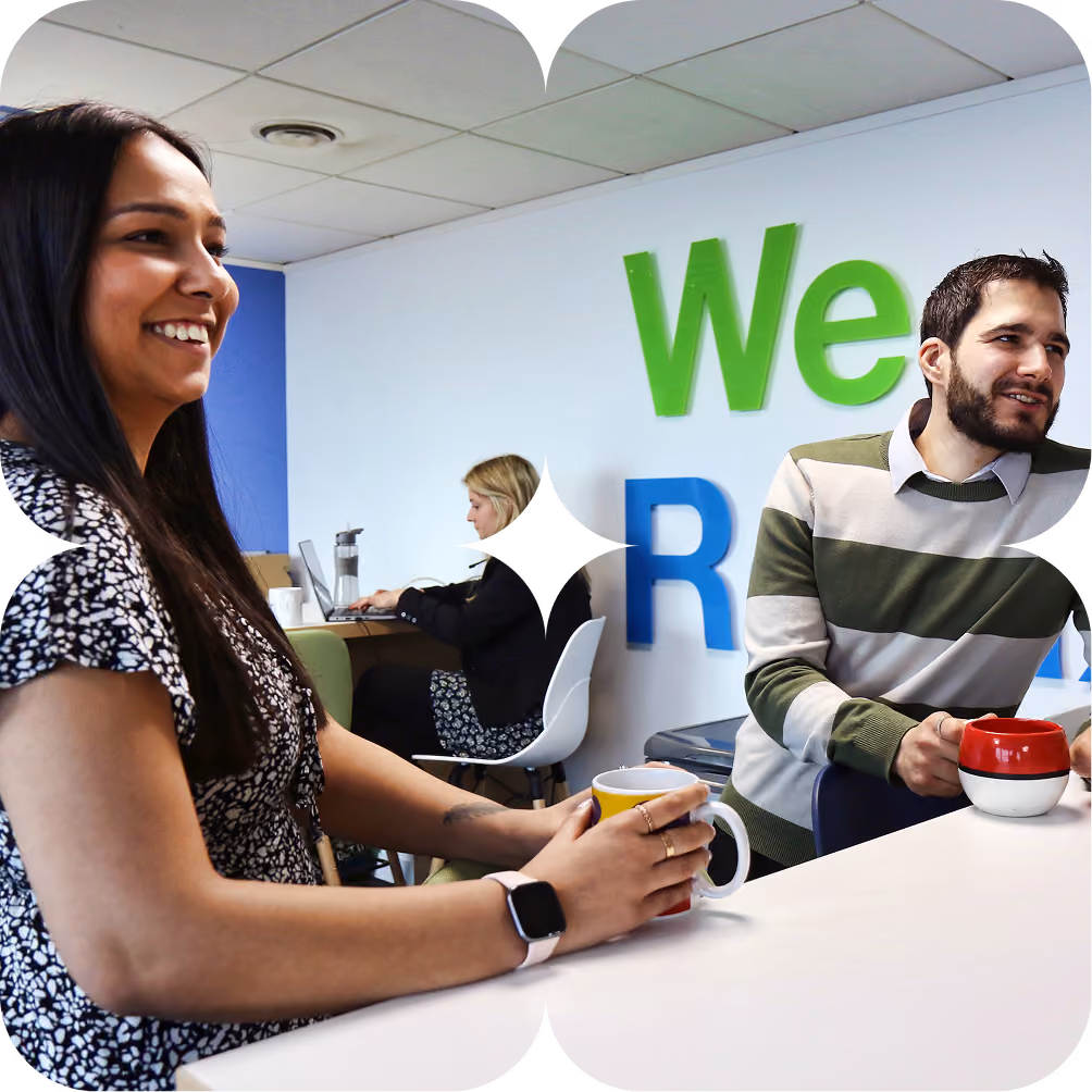 A woman and man smiling and leaning on a counter
