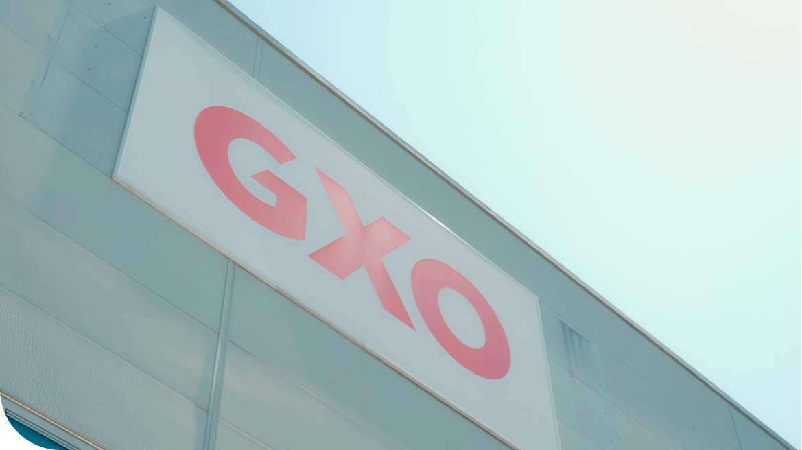 A low-angle view of a GXO company sign on the exterior of a building.