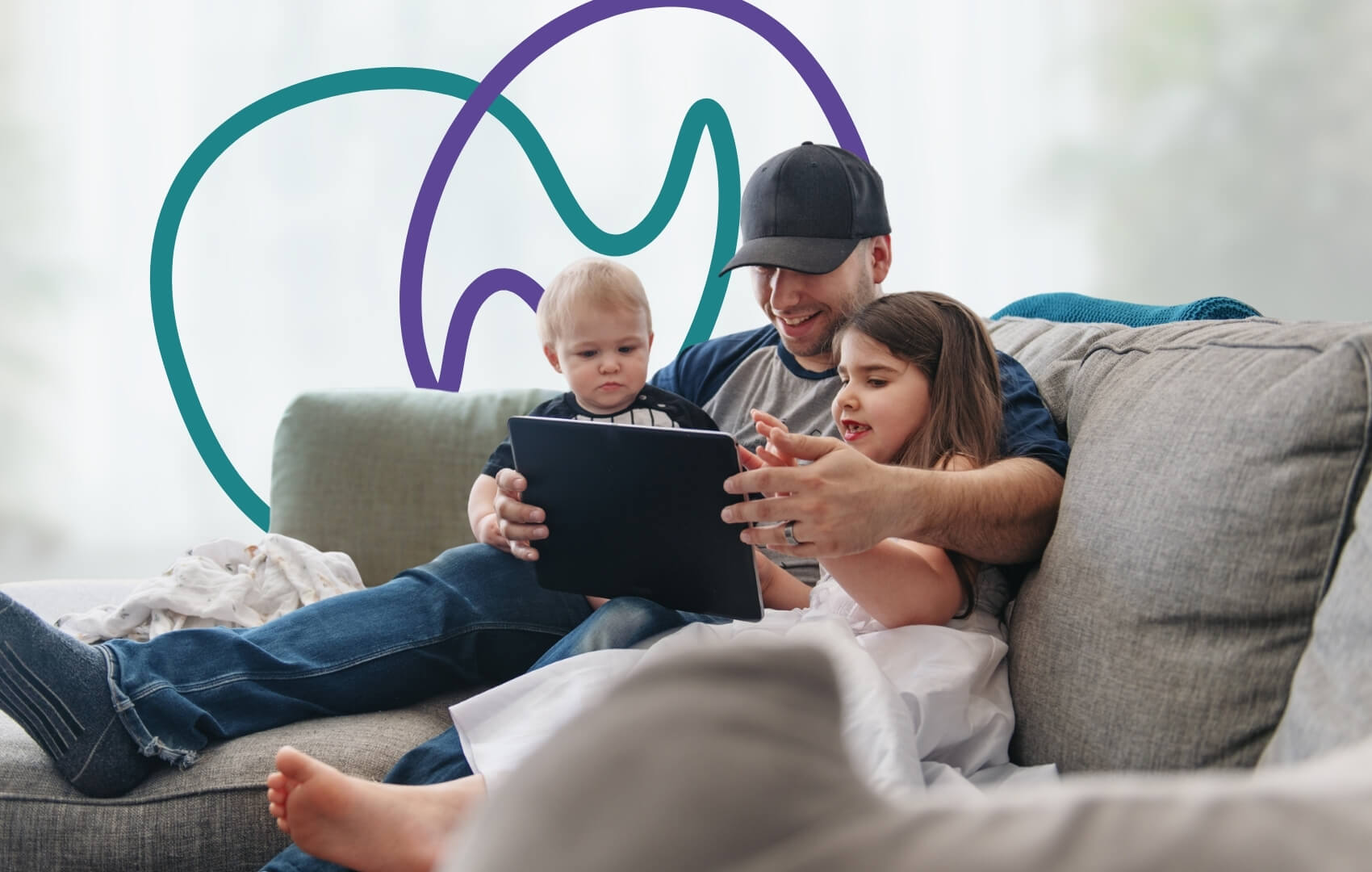 A father relaxes on the sofa with his two young children, all looking at a tablet together.