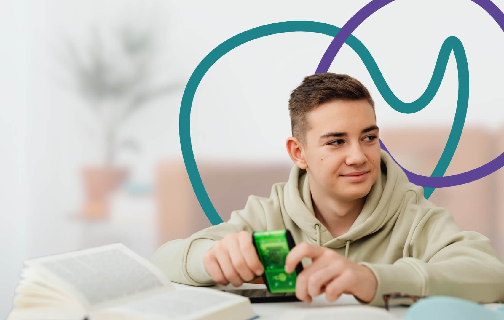 A teenage boy sits at a desk with books and a small fidget device
