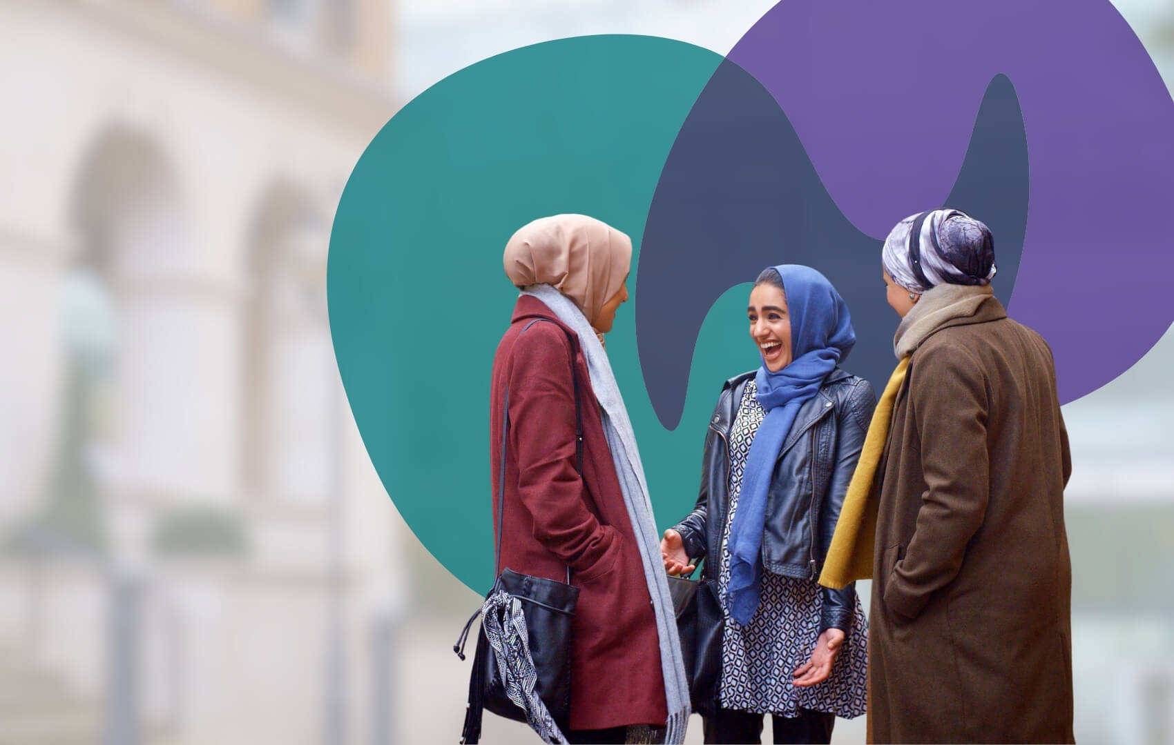 Three women stand together outdoors in conversation, one laughing openly.