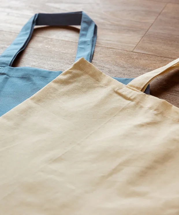 Blank cotton tote bags on a wood background