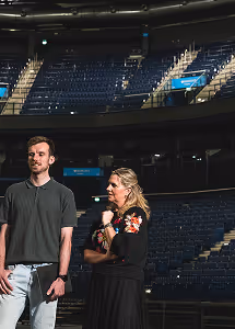 Man and woman standing in a dimly lit empty theater with rows of seats behind them.
