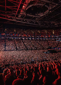 Crowded indoor concert venue with a large audience and stage lighting overhead.