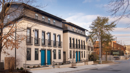Aerial watercolor illustration of a residential neighborhood with brick apartment buildings and houses surrounded by trees in autumn colors.