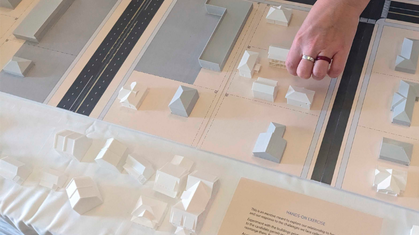 Aerial watercolor illustration of a residential neighborhood with brick apartment buildings and houses surrounded by trees in autumn colors.