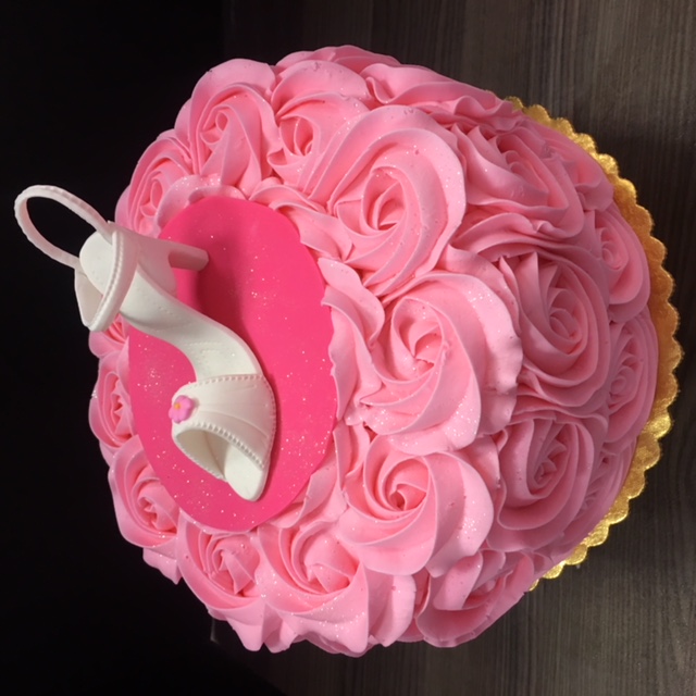 A custom cake piped with pink flowers and topped with a white heel