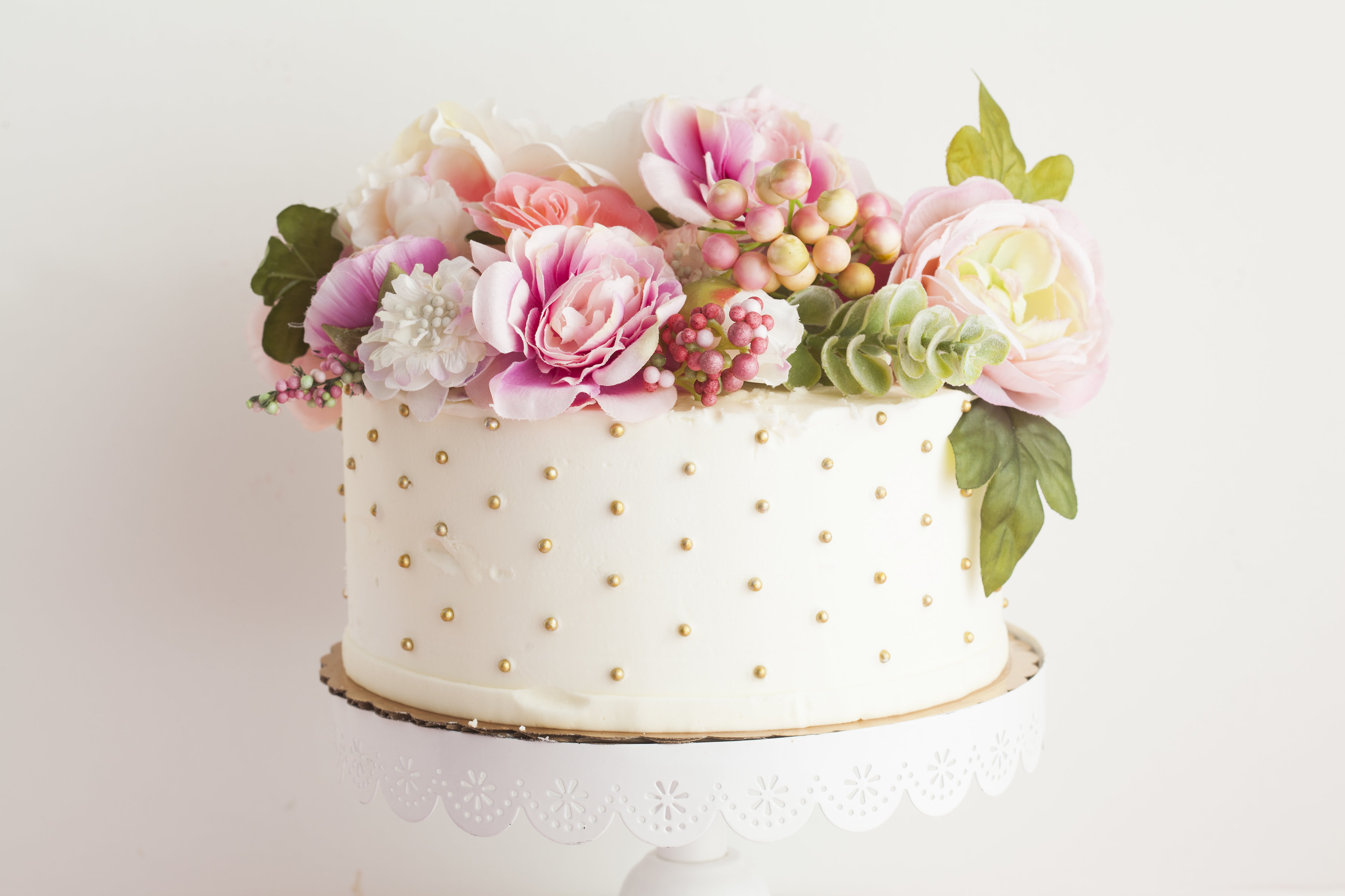 A single layer dotted cake topped with flowers by Pinkabella