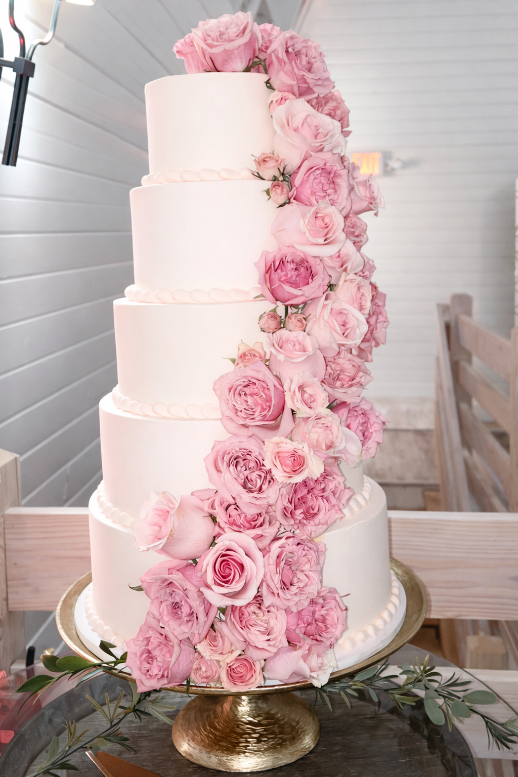 A 5 tier Pinkabella Wedding cake with pink roses cascading down