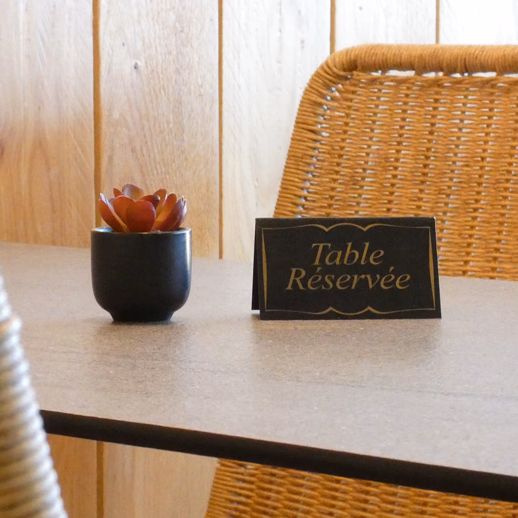 Chevalet « Table Réservée » posé sur une table du restaurant, à côté d'un succulent en pot noir