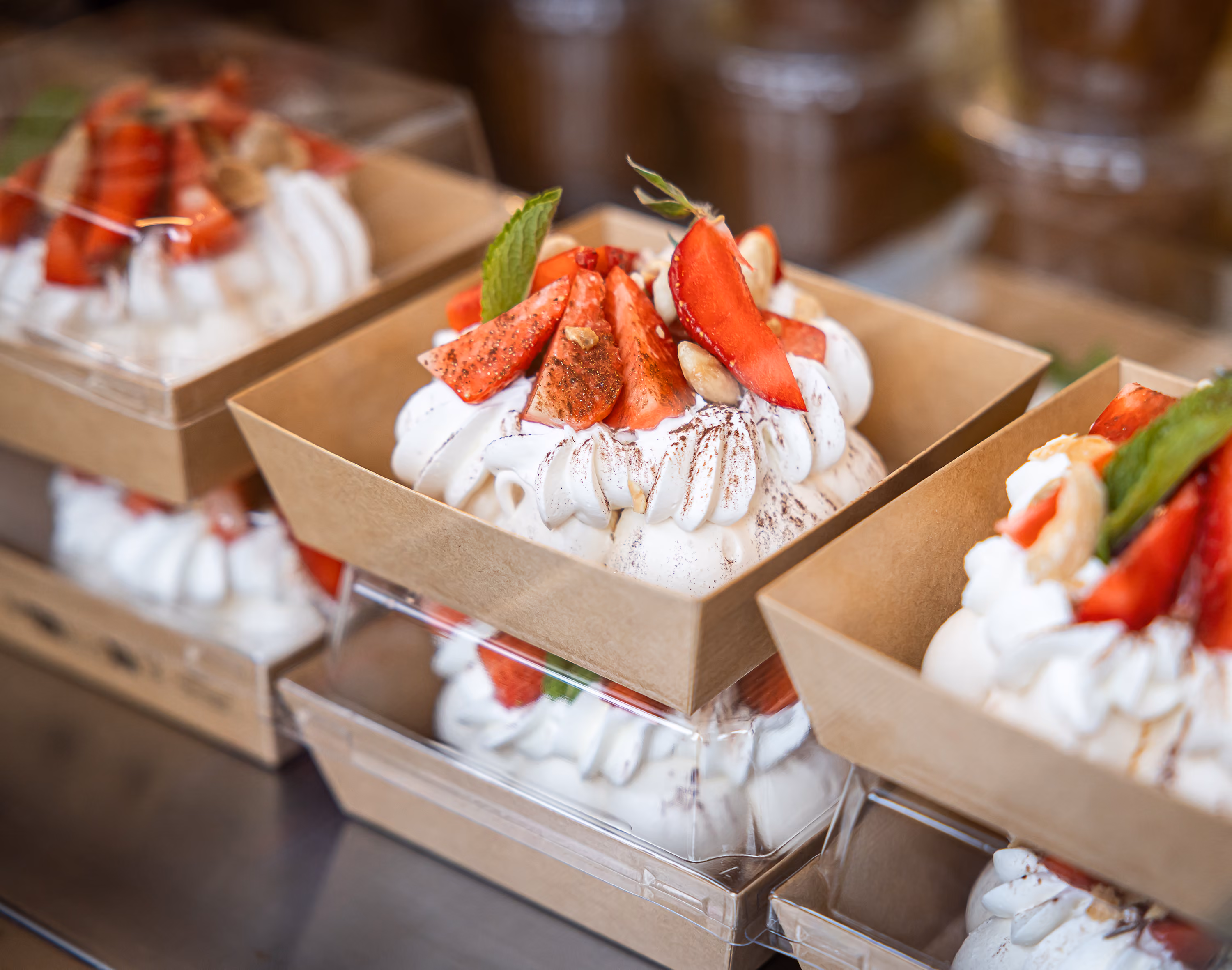 Pavlovas individuelles à la chantilly, fraises fraîches et menthe, présentées en barquettes kraft