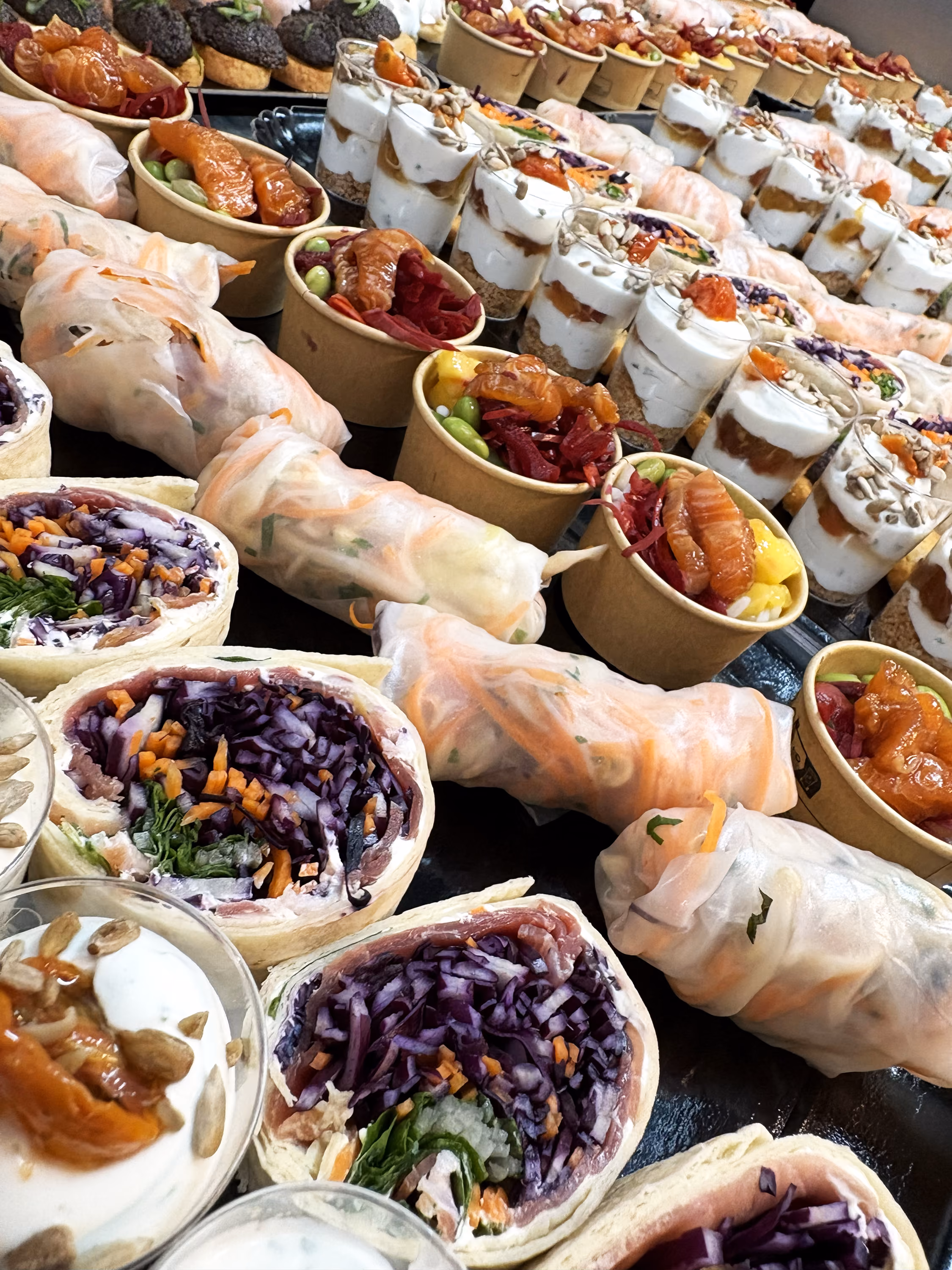 Buffet traiteur salé : wraps au chou rouge, rouleaux de printemps, bols de saumon et verrines aux graines
