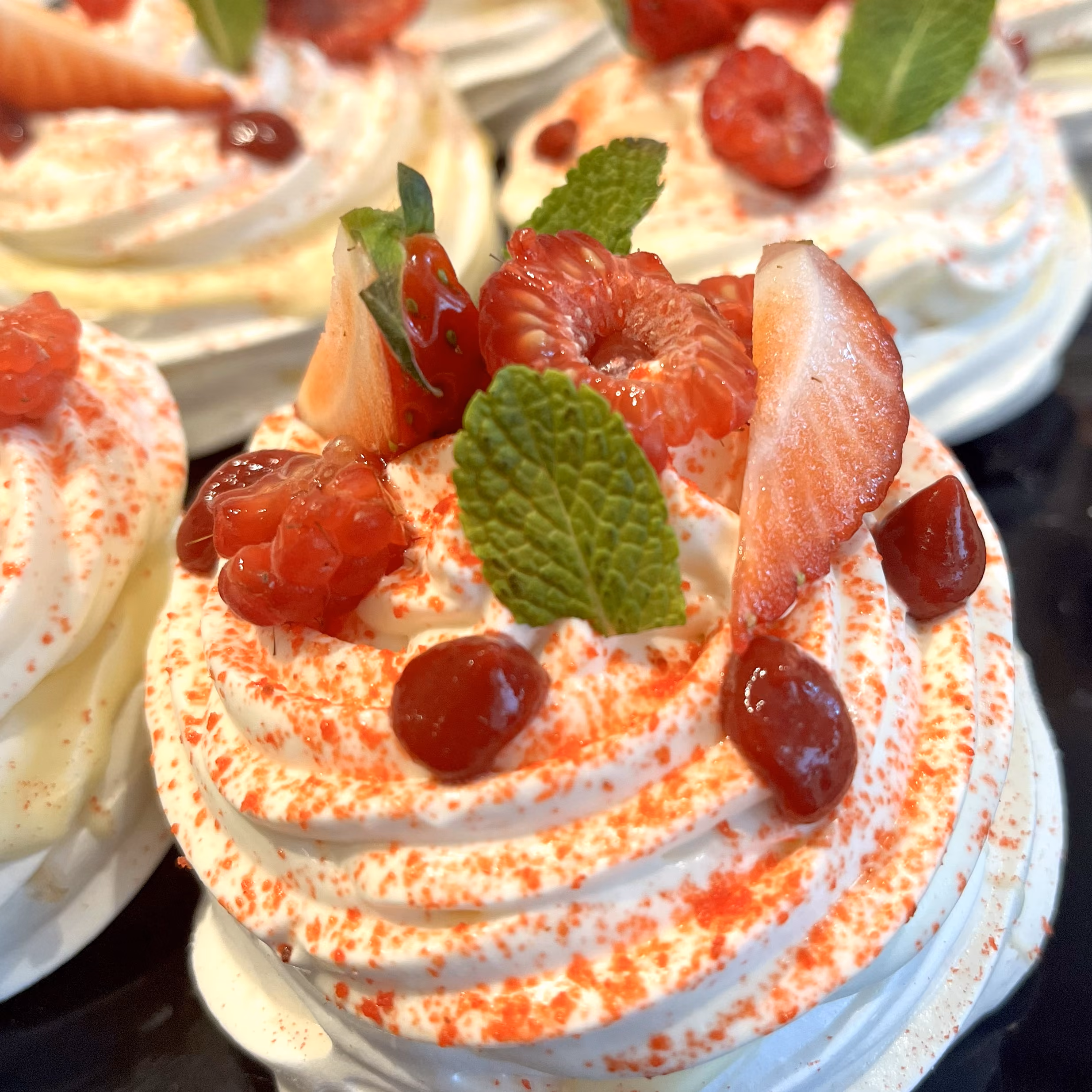Pavlovas aux fruits rouges : crème fouettée, fraises, framboises, grenade et menthe, en gros plan