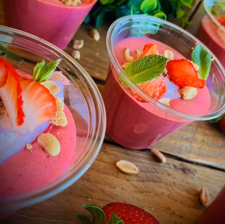 Verrines de mousse aux fruits rouges garnies de fraises fraîches, cacahuètes et menthe, sur plan en bois