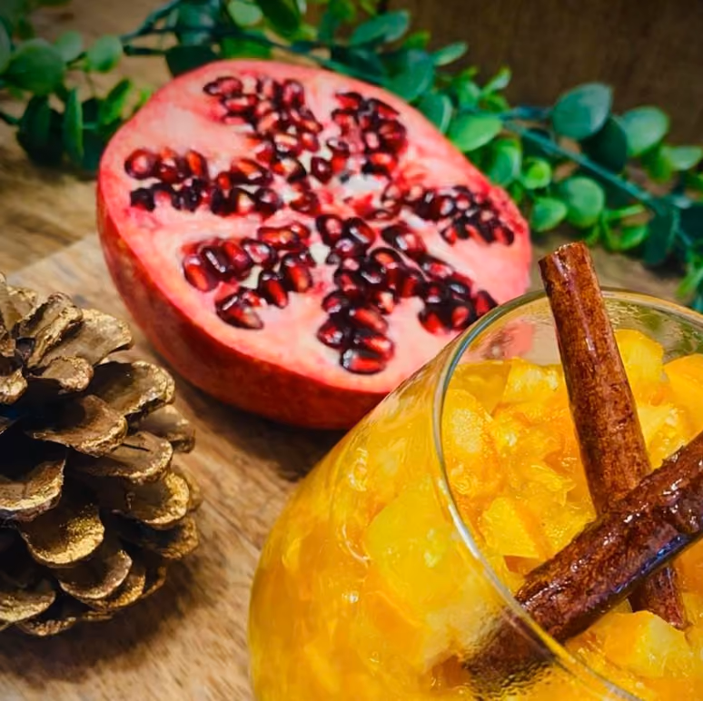 Verrine de compotée d'agrumes aux bâtons de cannelle, grenade coupée et pomme de pin dorée, ambiance hivernale