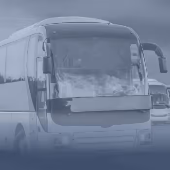 Großer Reisebus steht auf einem Parkplatz mit einem weiteren Bus im Hintergrund.