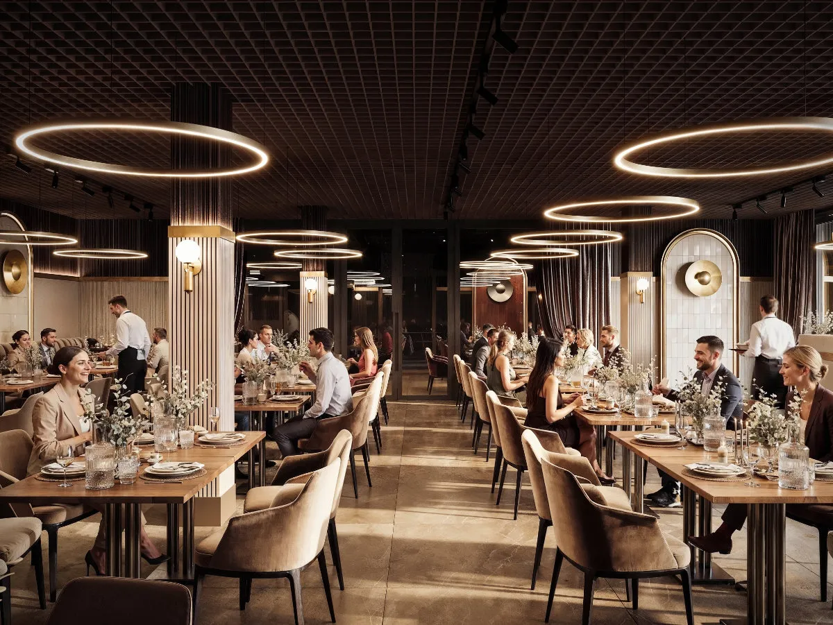 Elegancka sala bankietowa z nowoczesnym oświetleniem w kształcie świetlnych pierścieni, wypełniona gośćmi siedzącymi przy stołach i kelnerami obsługującymi.