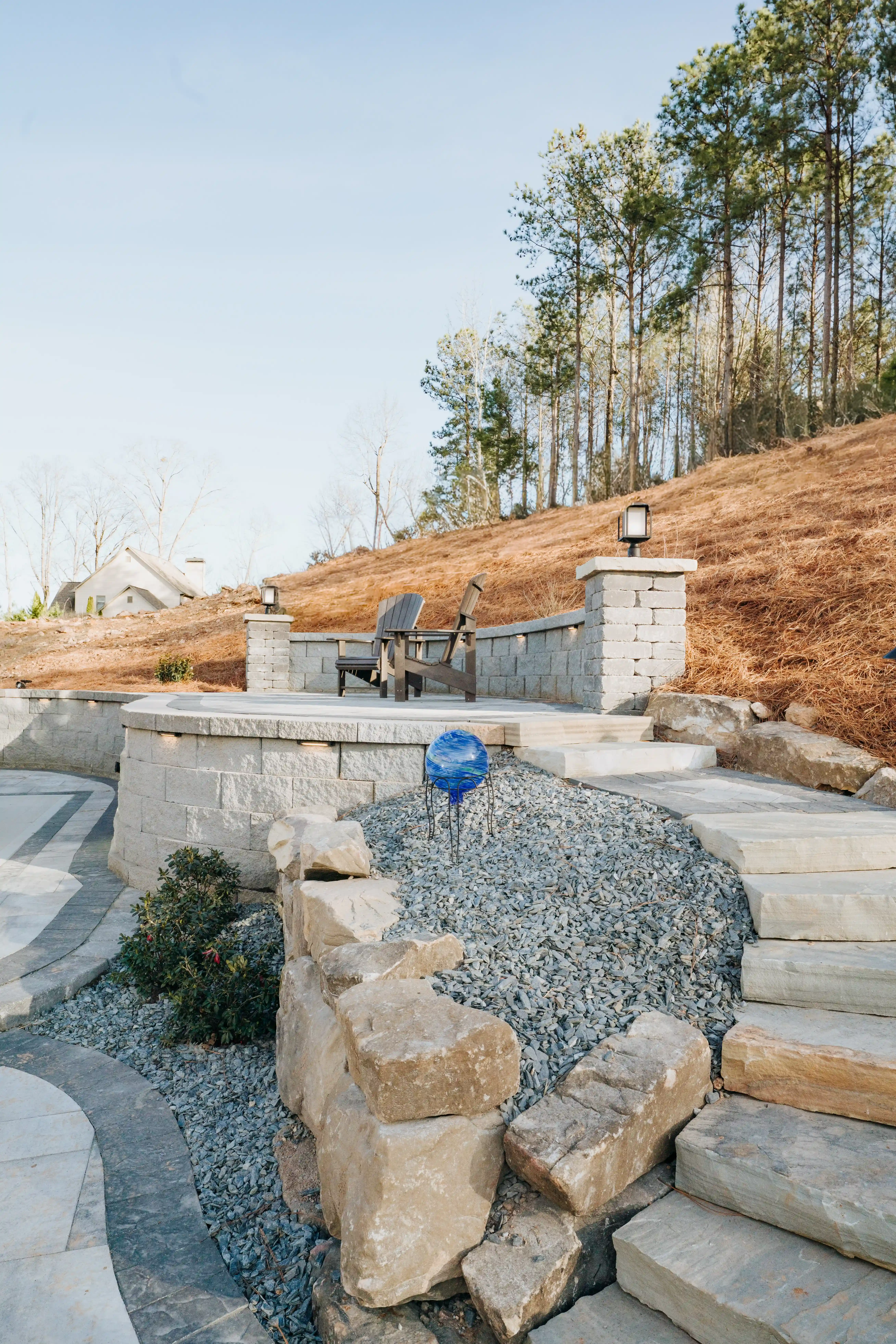 boulder wall with seating area and hill in background