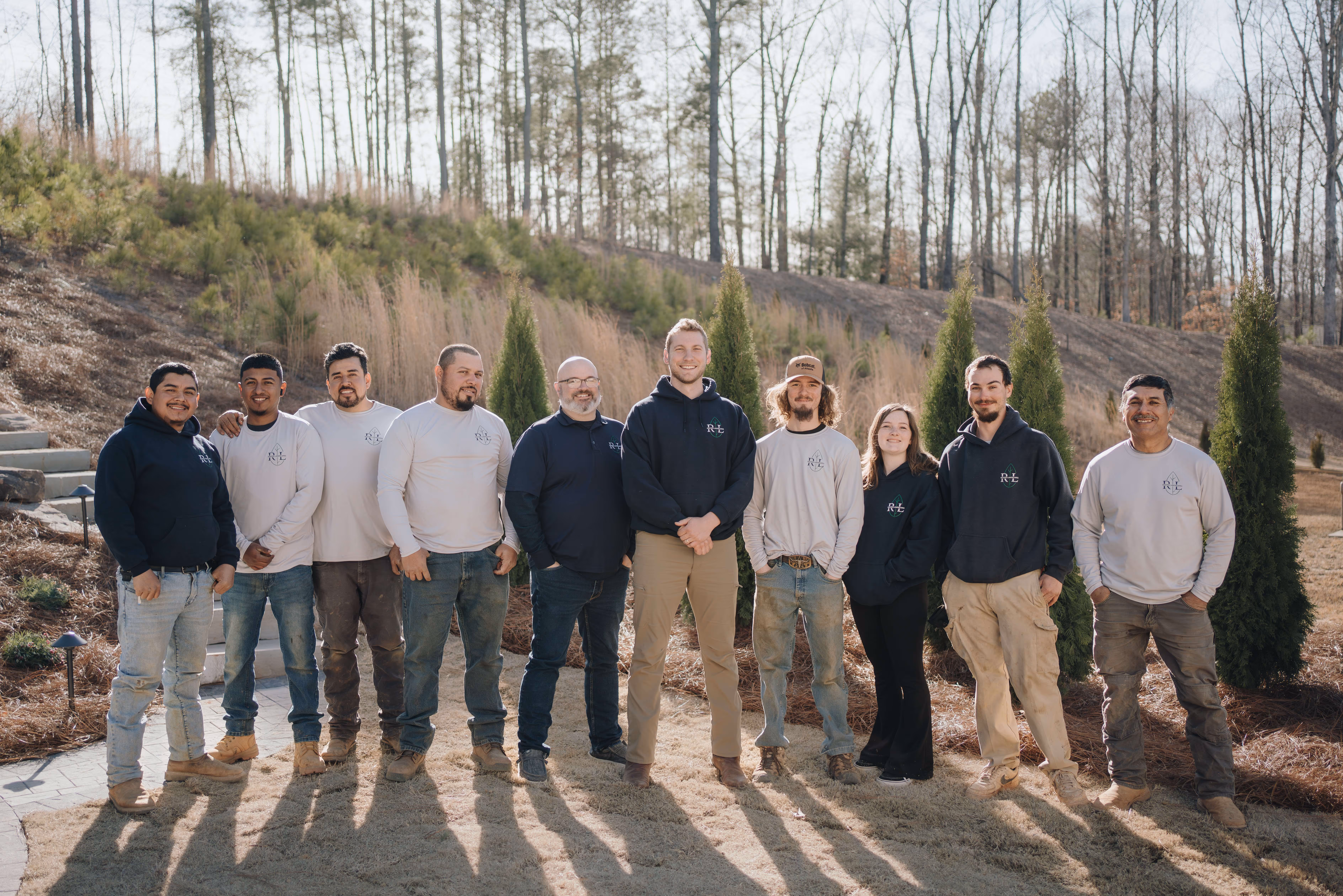 Group photo of Rooted team in grassy area with trees in background