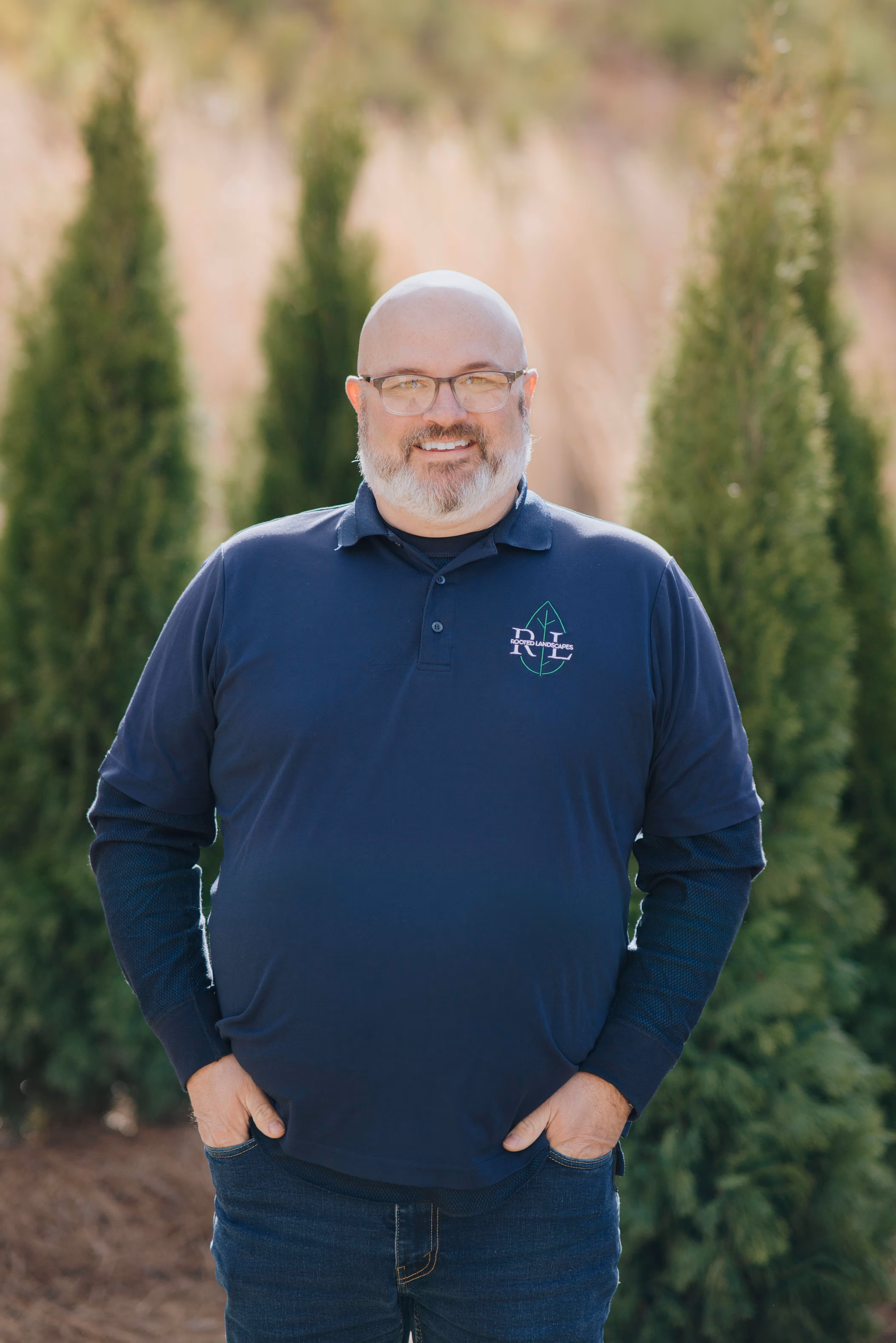 photo of man in blue shirt smiling with trees in background