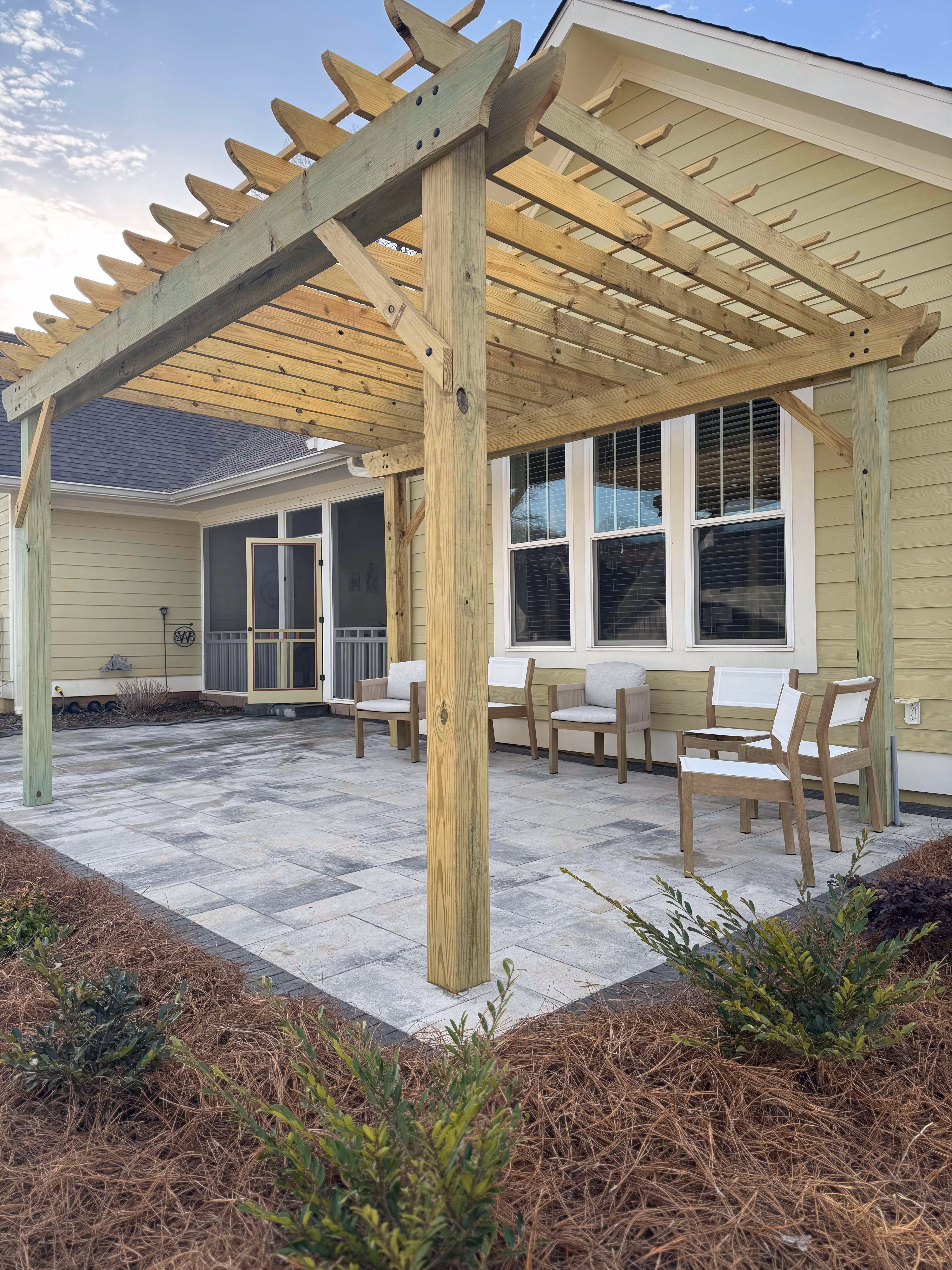 paver patio behind home under pergola