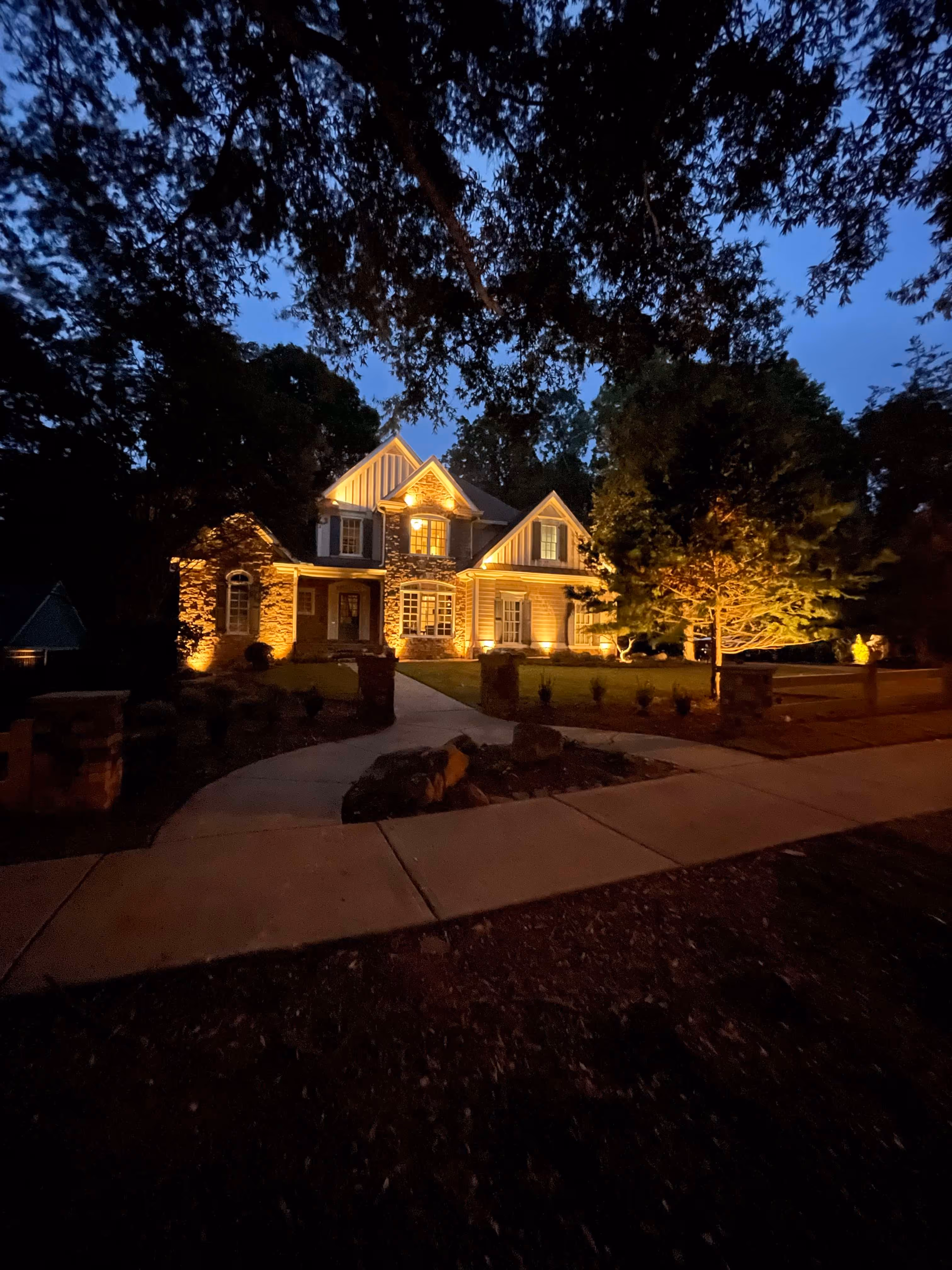 large home visible from street at night well lit by outdoor lighting