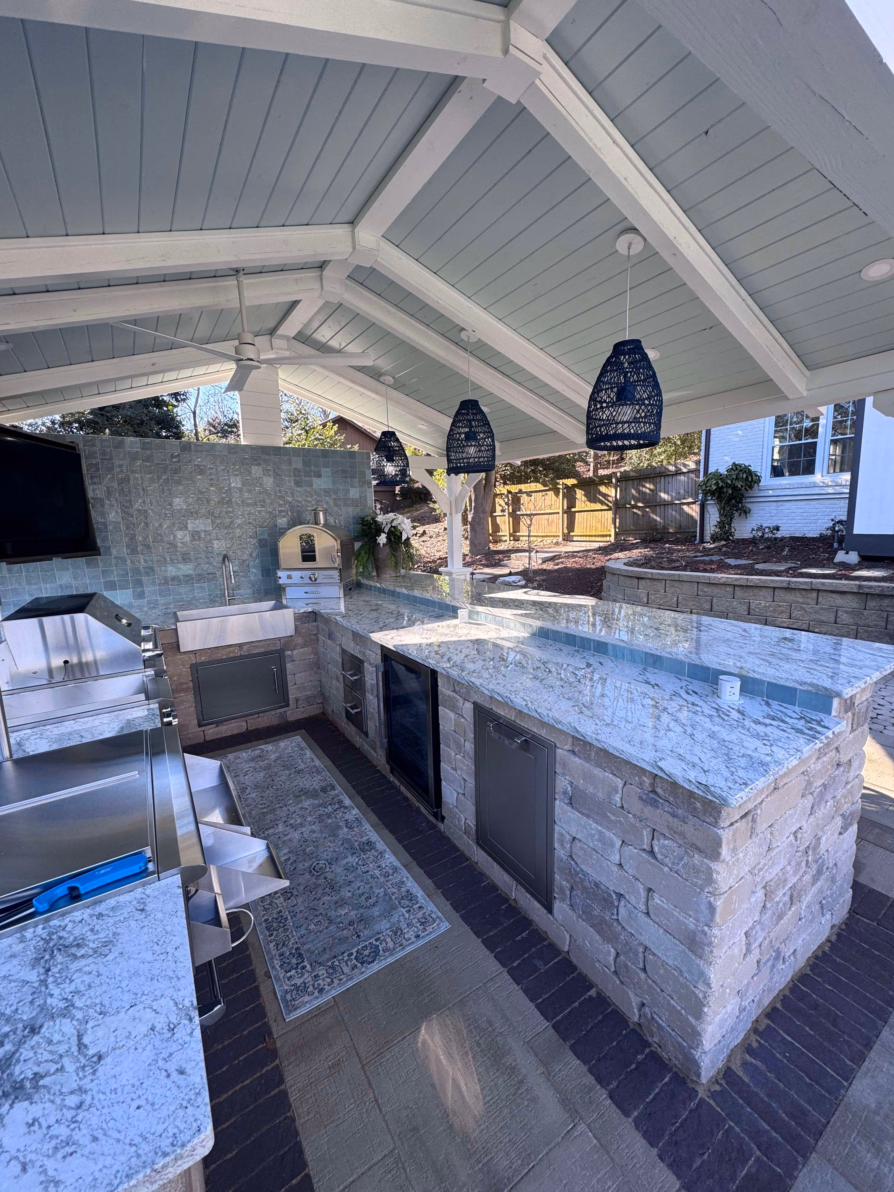 covered outdoor kitchen area with appliances bar and television