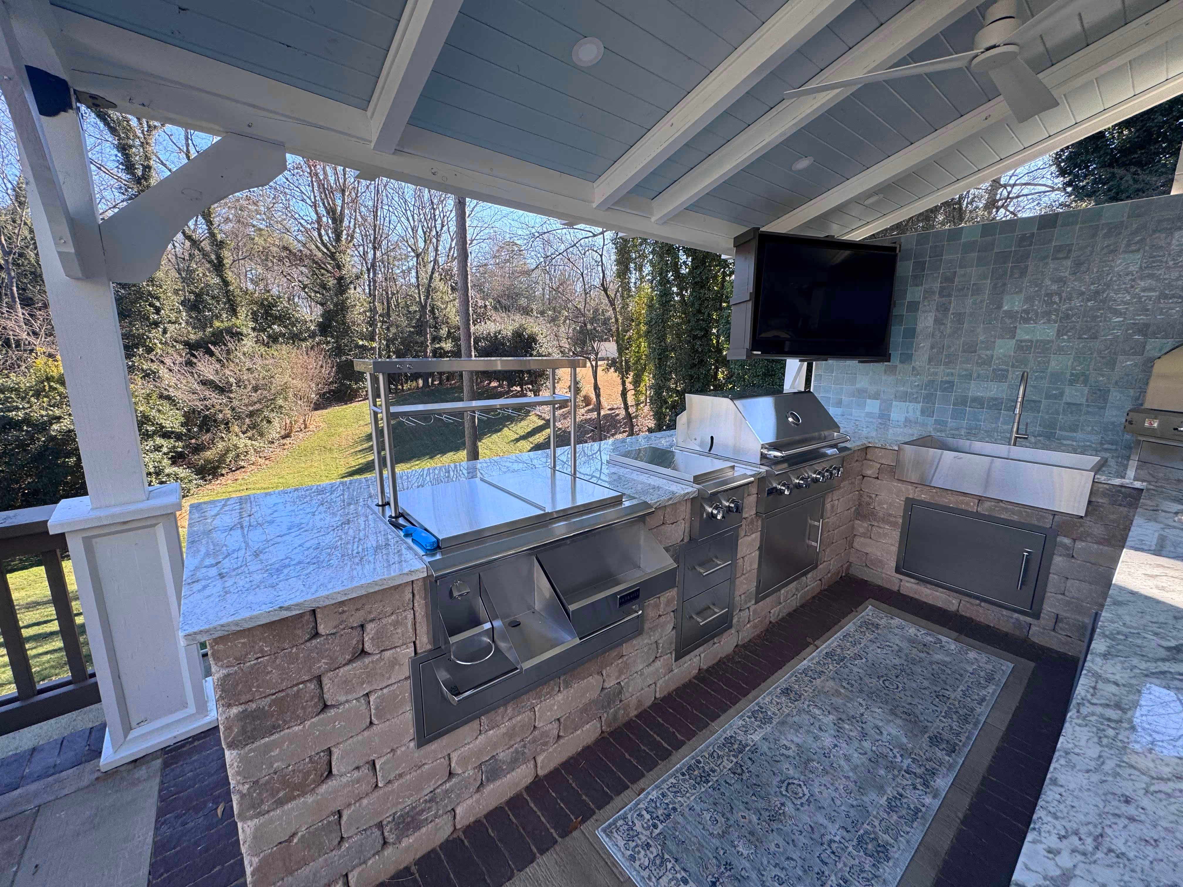countertop with appliances and television in outdoor kitchen