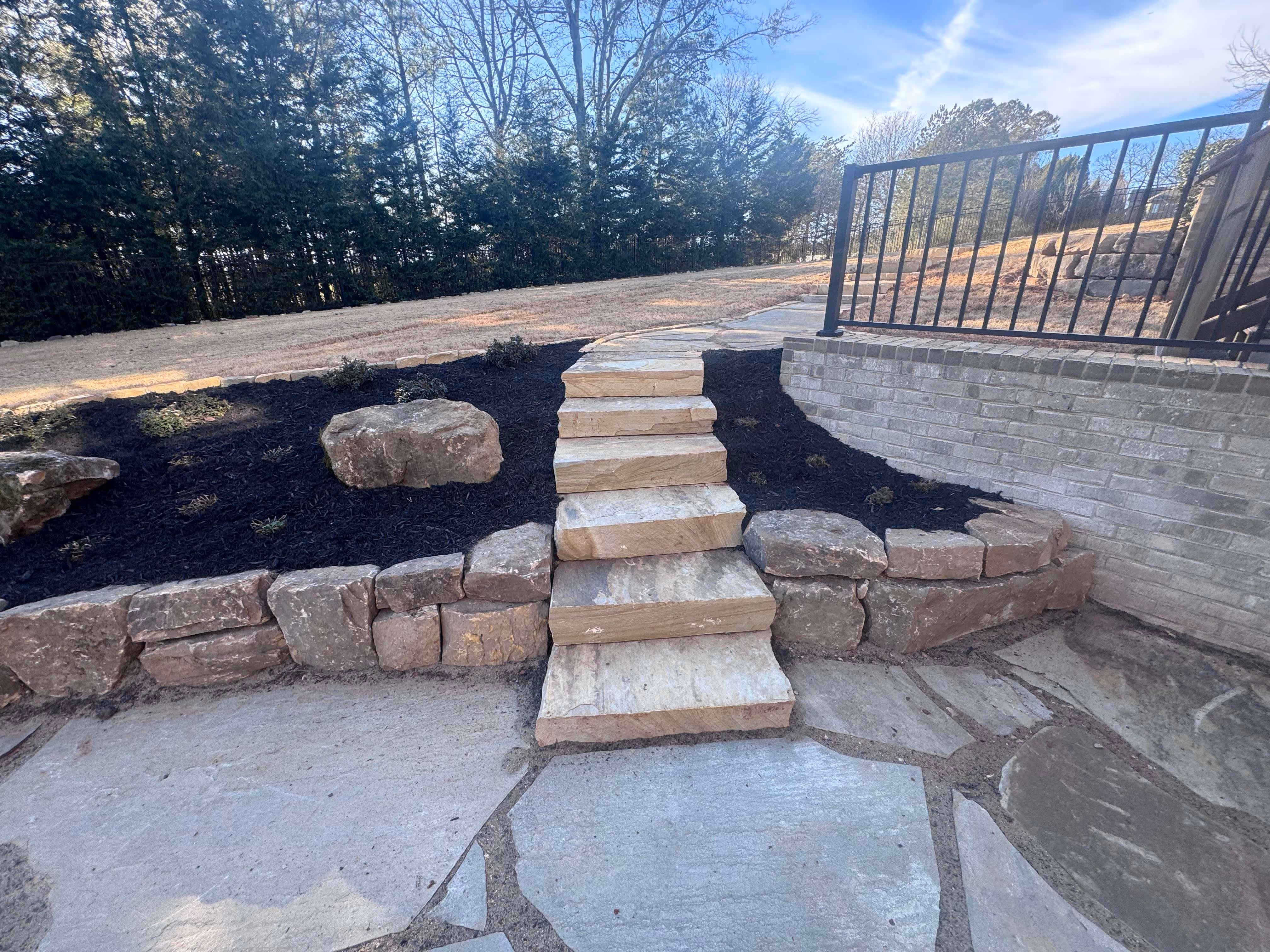 flagstone patio and staircase with boulder retaining wall