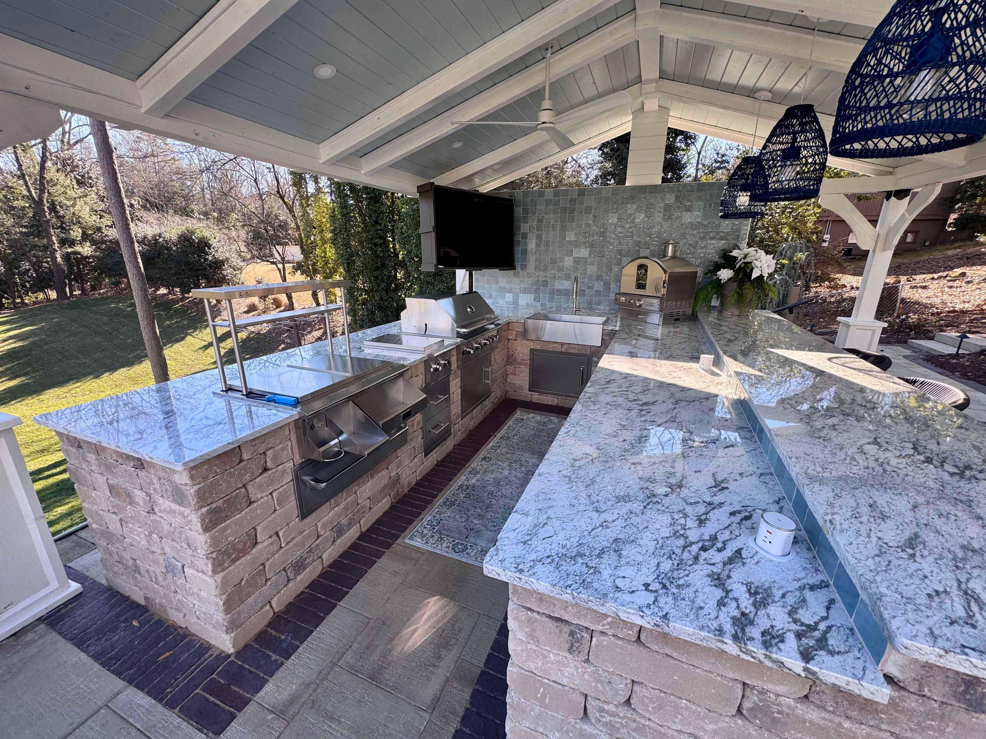 covered outdoor kitchen with television grill and kitchen appliances
