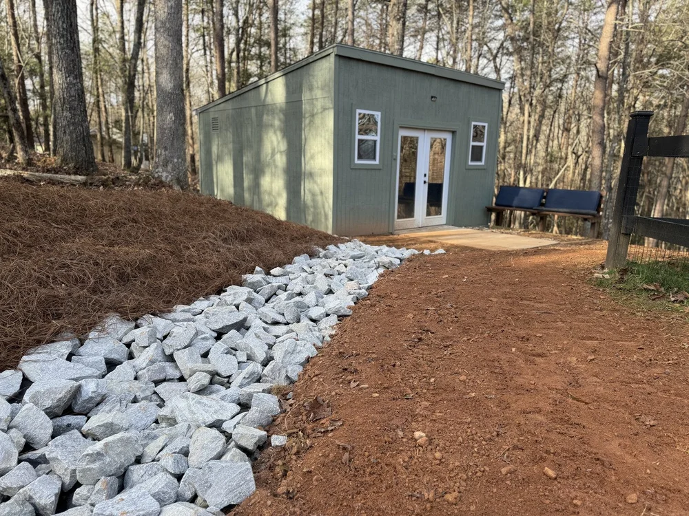 rock drainage trench next to pine straw in front of building