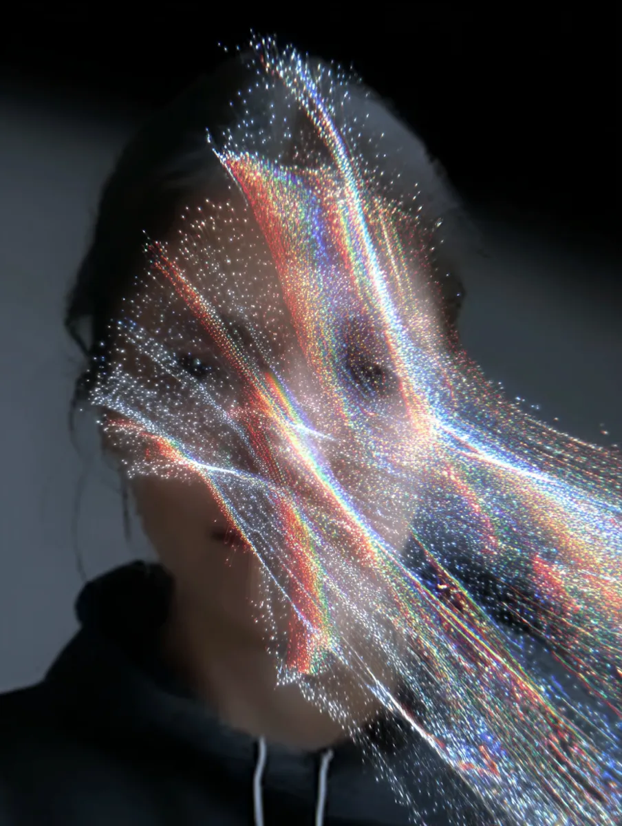 Abstract digital portrait of a person obscured by flowing, multicolored light particles on a dark background.