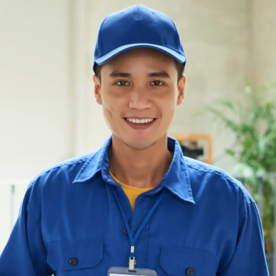 Smiling young man wearing a blue cap and blue work shirt with a name badge.