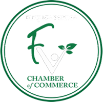 Fuquay-Varina Chamber of Commerce logo with stylized FV and green leaf inside circular border.