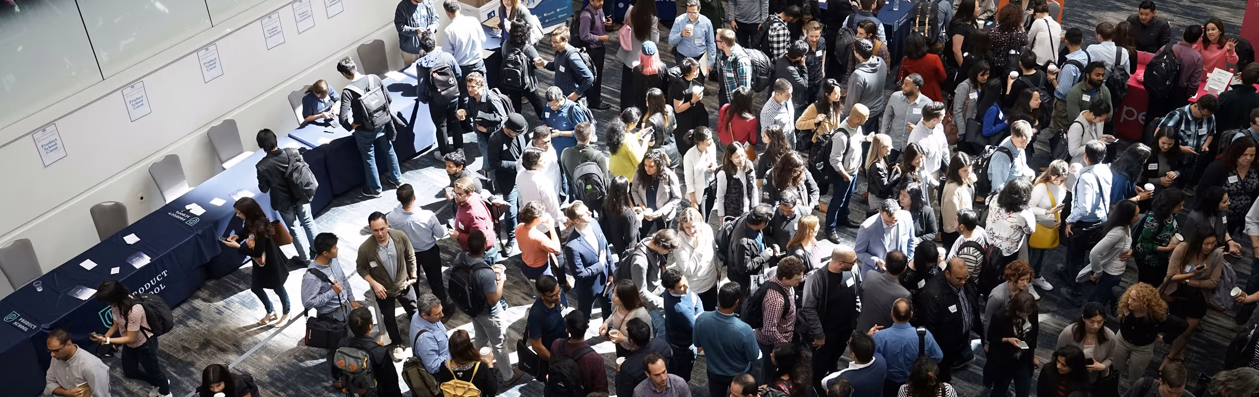 Large group of people attending a networking event with tables labeled Product School Career Center.