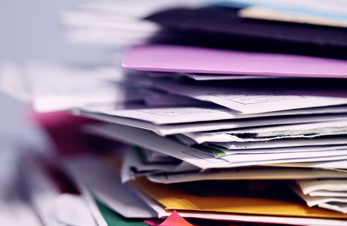 Close-up of a disorganized pile of various papers and envelopes.