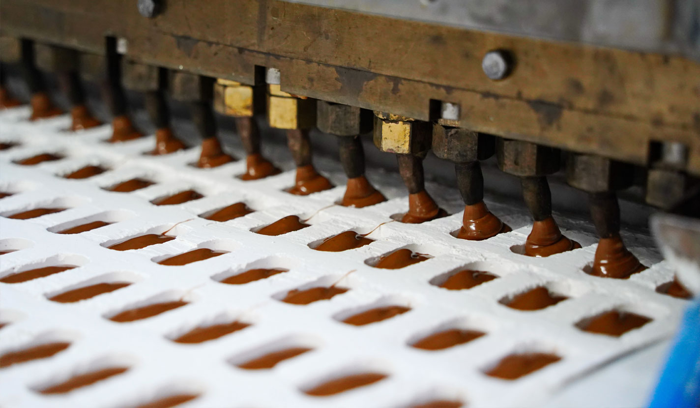 Rows of square biscuits on a conveyor belt inside a food processing factory.