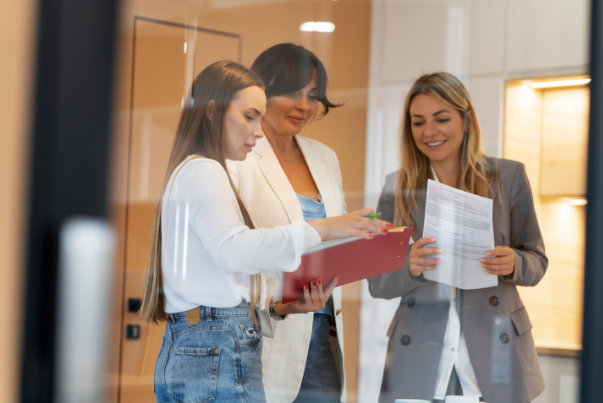 Tres mujeres mirando documentos para representar programas de internado.