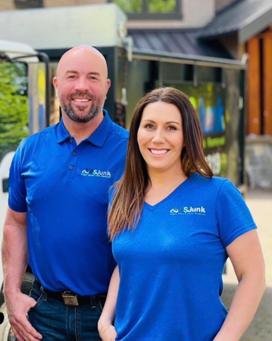Smiling man and woman wearing blue SJunk shirts standing outside in front of a truck.